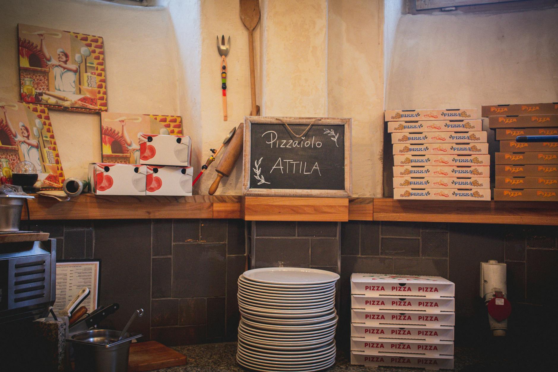 Przytulne wnętrze włoskiej pizzerii z pudełkami na pizzę na ladzie Przytulne wnętrze włoskiej pizzerii z pudełkami na pizzę na ladzie