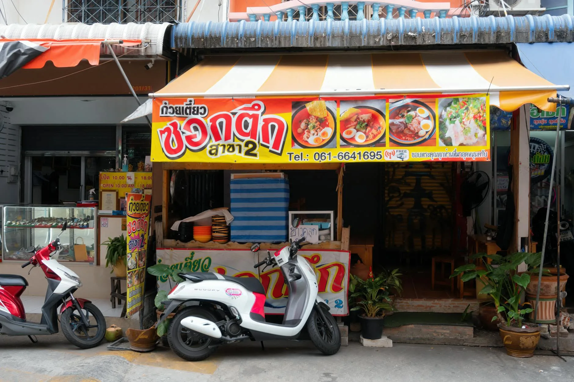 Ulica z barwną knajpką z makaronem i skuterami zaparkowanymi przed wejściem