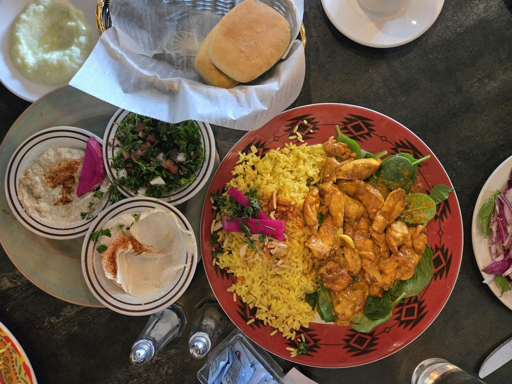 Kolorowy talerz kuchni bliskowschodniej z kurczakiem, ryżem, hummusem i chlebem