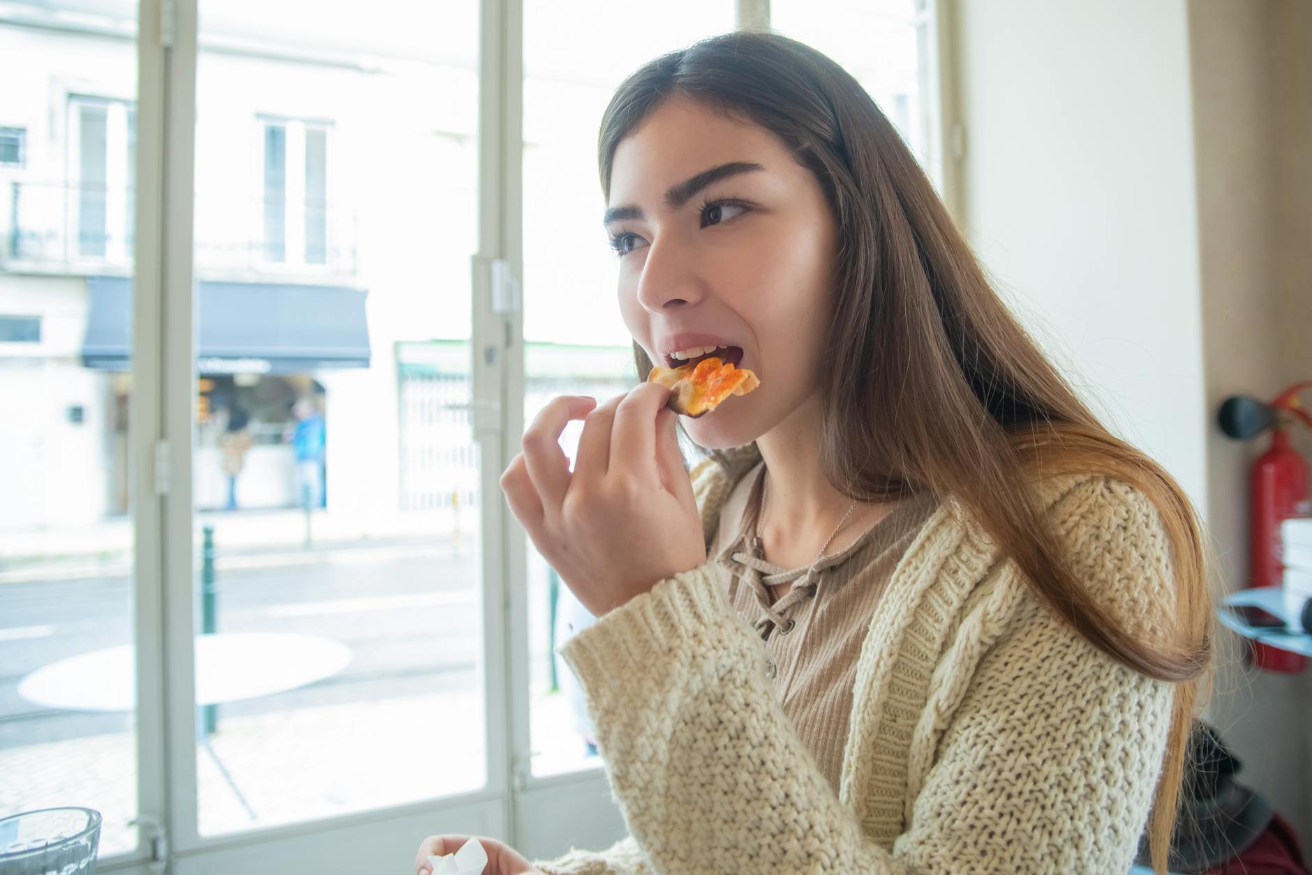 Młoda kobieta zjada ze smakiem kawałek pizzy w restauracji